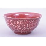 A CHINESE COPPER RED GLAZE BOWL, the exterior with raised decoration depicting dragon, phoenix and