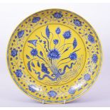 A LARGE CHINESE MING STYLE YELLOW GROUND BLUE AND WHITE DISH, the centre painted with a floral spray