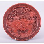 A CHINESE CINNABAR LACQUER CIRCULAR DISH, decorated with a landscape setting, the underside with