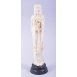 A CHINESE CARVED IVORY FIGURE OF A SAGE holding a flower, mounted to a hardwood base, 23cm high.