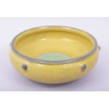 A CHINESE YELLOW AND GREEN GLAZED BOWL, the exterior with six raised bosses, 23cm diameter.