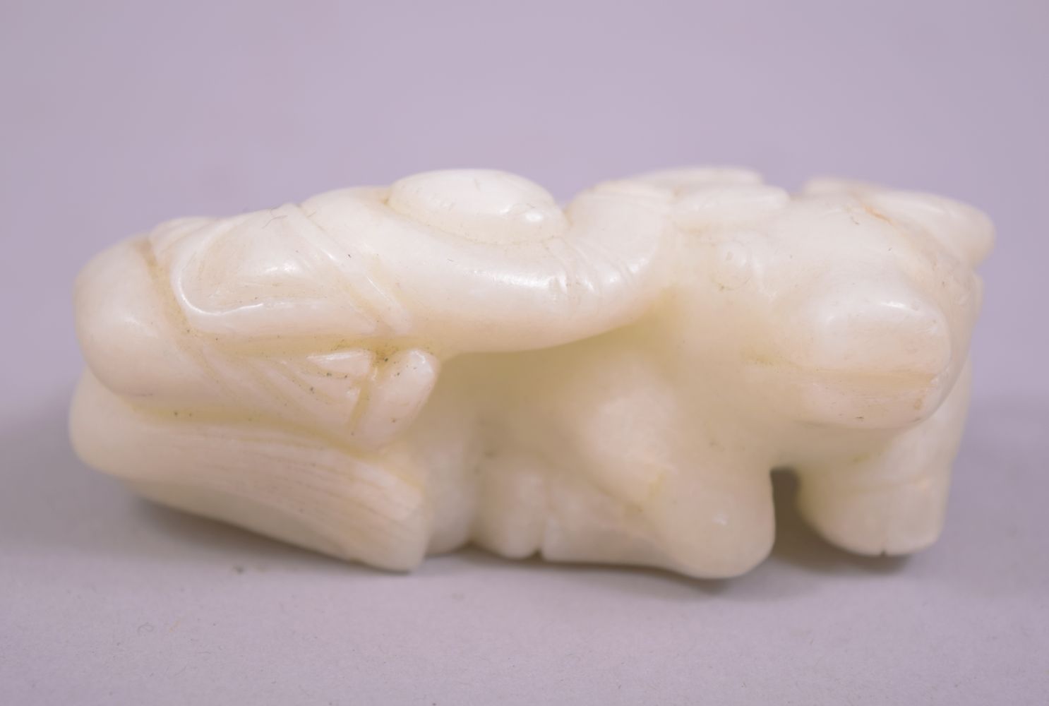 A SMALL CHINESE JADE CARVING OF A BUFFALO, with a figure astride, 8cm long.