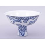 A CHINESE MING STYLE BLUE AND WHITE PORCELAIN STEM CUP, decorated with dragons amongst stylised