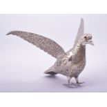 AN INDIAN ENGRAVED AND CHASED WHITE METAL MODEL OF A BIRD, with wings outstretched, 24cm long.