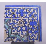 AN ISLAMIC BLUE AND WHITE GLAZED POTTERY TILE, with floral decoration, raised on a metal stand, tile