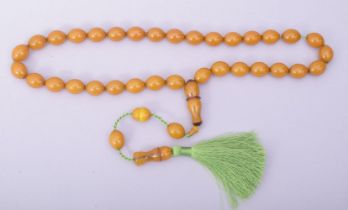 AN ISLAMIC AMBER COLOUR BAKELITE SET OF TASBIH PRAYER BEADS, comprising of 35 oval beads, one shaped