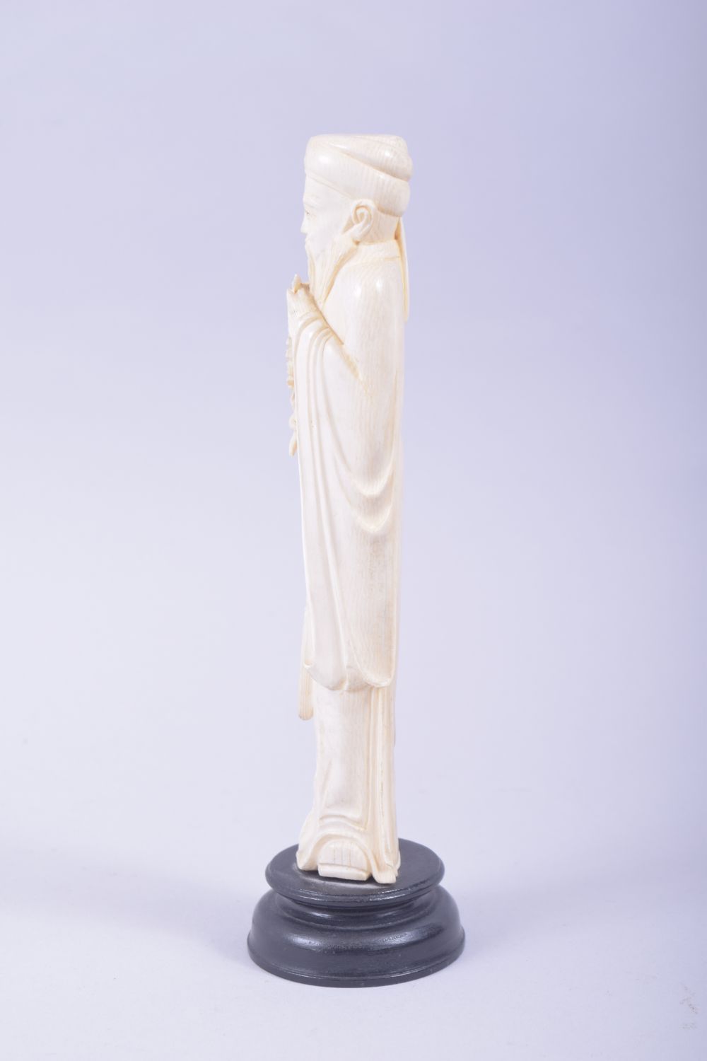 A CHINESE CARVED IVORY FIGURE OF A SAGE holding a flower, mounted to a hardwood base, 23cm high. - Image 4 of 7