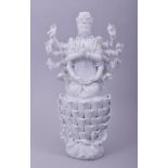 A BLANC DE CHINE PORCELAIN FIGURE of a deity, sat upon a petal base, 23.5cm high.