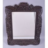 A CHINESE CARVED AND PIERCED WOODEN FRAMED MIRROR, the frame carved figures, temples and foliate
