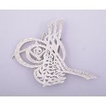 AN ISLAMIC WHITE METAL CLIP ORNAMENT.