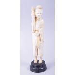 A CHINESE CARVED IVORY FIGURE OF A SAGE holding a basket aloft, mounted to a hardwood base, 23.5cm