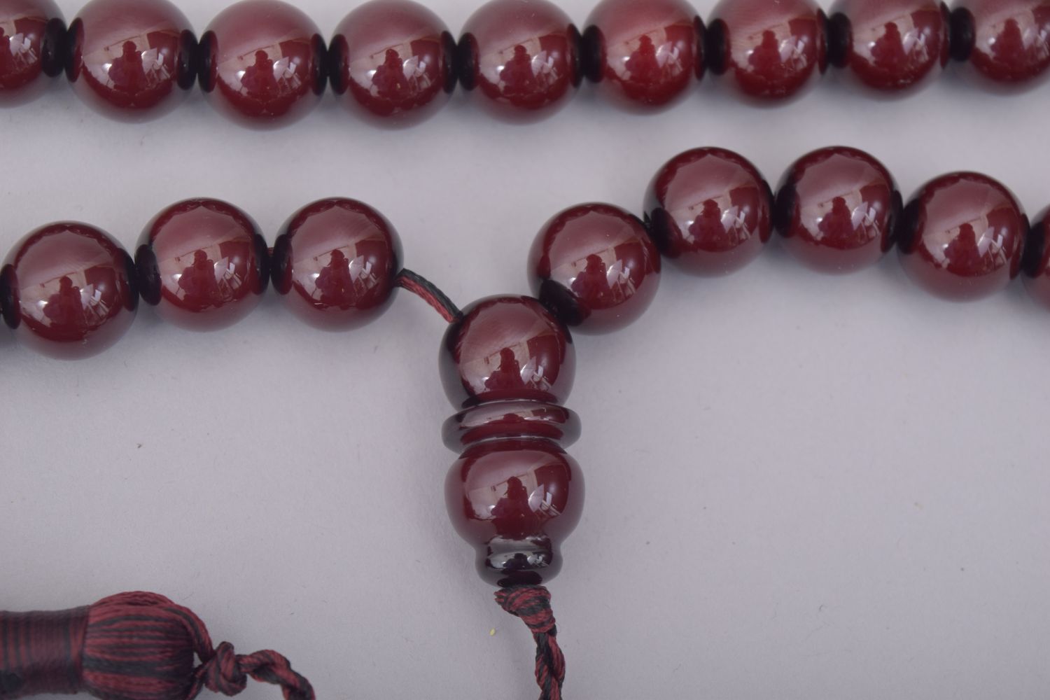 AN ISLAMIC CHERRY BAKELITE SET OF TASBIH PRAYER BEADS, comprising of 34 beads, two small dividing - Image 3 of 3