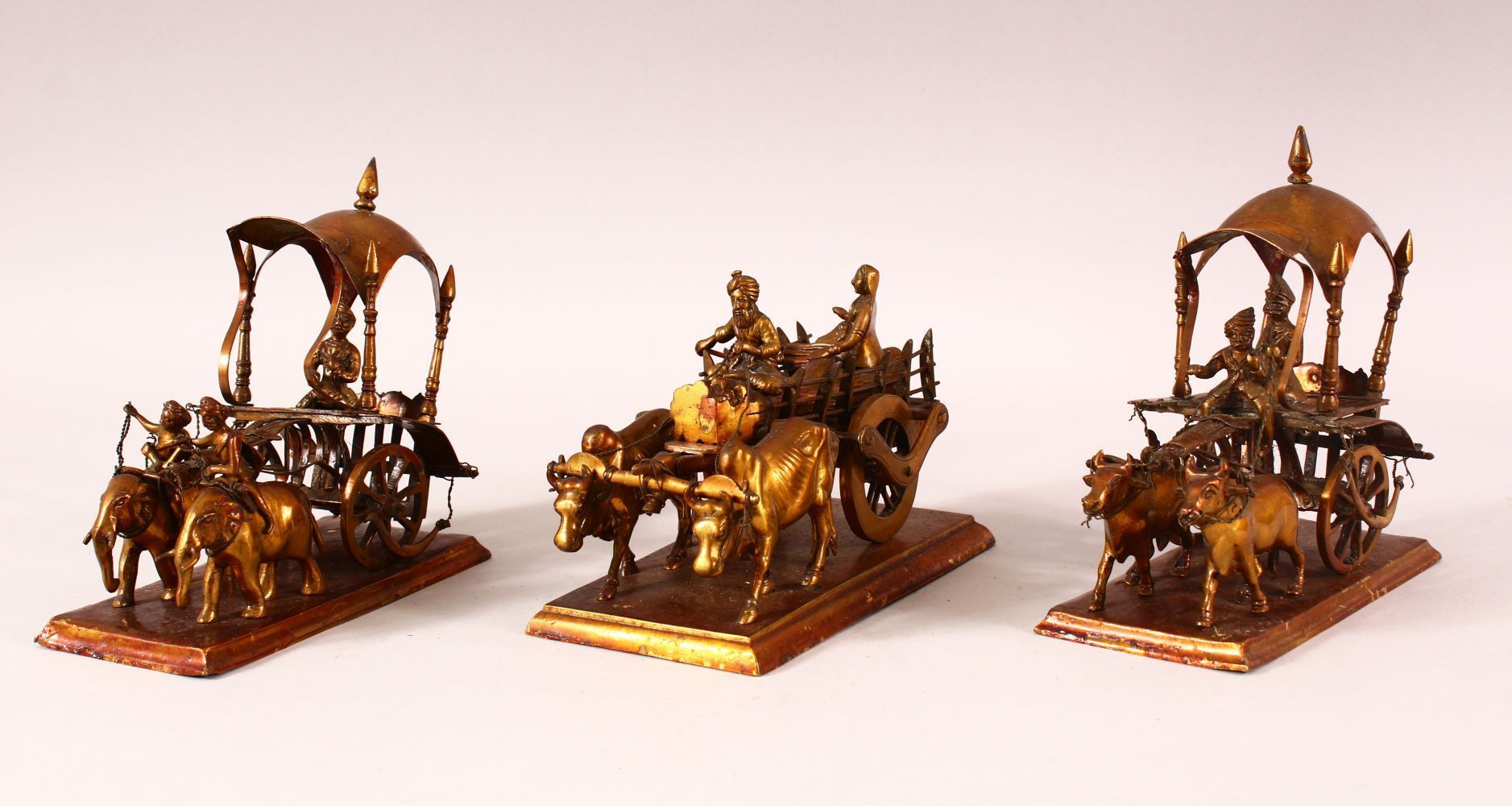 THREE 19TH CENTURY INDIAN METAL MODELS OF CARTS, each cart drawn by a variety of animals, largest