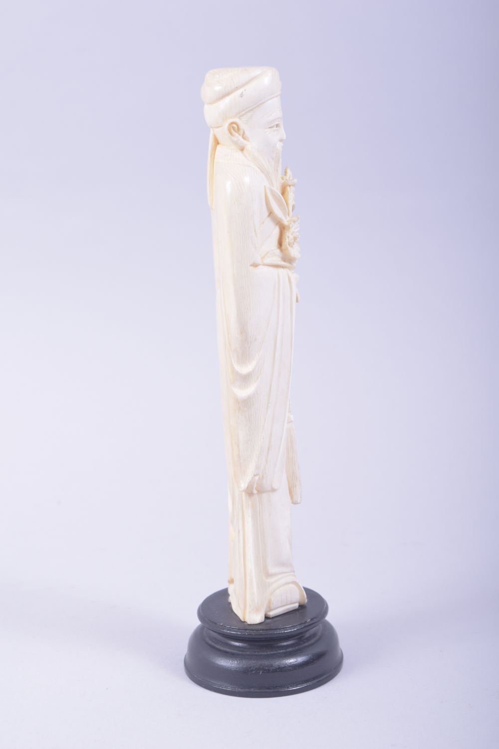 A CHINESE CARVED IVORY FIGURE OF A SAGE holding a flower, mounted to a hardwood base, 23cm high. - Image 2 of 7