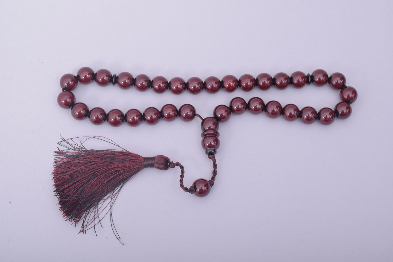 AN ISLAMIC CHERRY BAKELITE SET OF TASBIH PRAYER BEADS, comprising of 34 beads, two small dividing - Image 2 of 3