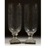 A PAIR OF CUT GLASS STORM LANTERNS on stepped square bases. 13ins high.