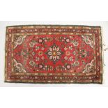 A SMALL PERSIAN RUG, red ground with floral decoration. 4ft 5ins x 2ft 7ins.