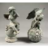 A PAIR OF PAINTED CAST IRON FAIRIES on a ball. 12ins high.