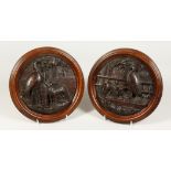 A PAIR OF BLACK FOREST CARVED WOOD CIRCULAR PLAQUES, depicting Aesop's fable of the Fox and Stork.
