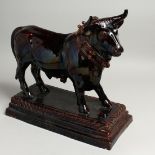 A ROYAL PORTUGUESE POTTERY BULL DECANTER on a rectangular base. 15ins long.