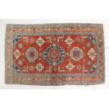 A SMALL PERSIAN RUG, red ground with geometric decoration. 4ft 2ins x 2ft 7ins