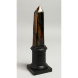 A GOOD TIGER'S EYE OBELISK, 5ins high. on a wooden base.