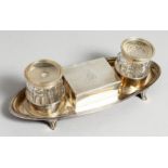 A GEORGE III BOAT SHAPED TWO BOTTLE INKSTAND, the centre with a box with rising lid. 7.5ins long.