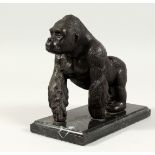 A BRONZE GORILLA on a marble base. 6ins high.