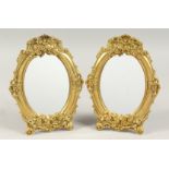 A PAIR OF GILDED METAL OVAL MIRRORS. 9ins long.