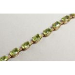 A GOLD AND PERIDOT LINE BRACELET.