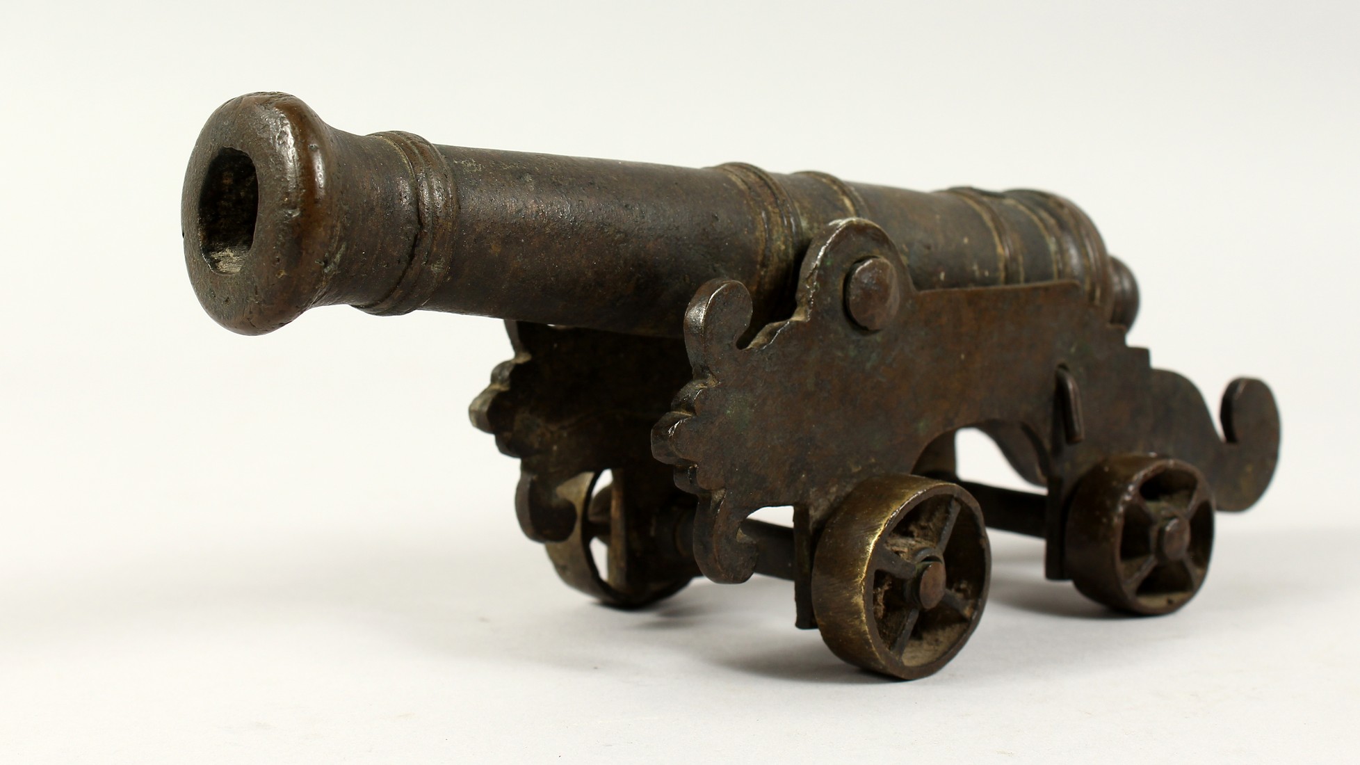 A SMALL EARLY BRONZE STARTER CANNON on bronze stand. 10ins long.