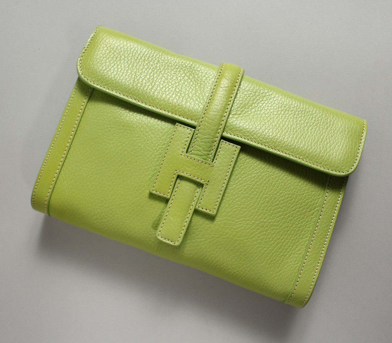 A GREEN LEATHER CLUTCH BAG and strap. 24cm long x 17cm high.