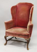 A GEORGE III MAHOGANY FRAMED WING ARMCHAIR, with crimson velvet upholstery, carved cabriole front