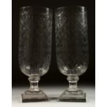 A PAIR OF SHELL CUT GLASS STORM LAMPS on stepped square bases. 16ins high.