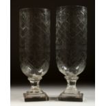 A PAIR OF GLASS STORM LAMPS on stepped square bases. 13ins high.