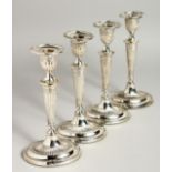 A SET OF FOUR OVAL SILVER CANDLESTICKS on loaded bases. 7.5ins high, Sheffield, 1907.