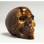 A TIGER’S EYE CARVED SKULL. 8cm long.