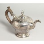 A GEORGE II CIRCULAR TEA POT AND COVER with repousse decoration and pineapple finial. London
