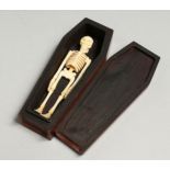 A SMALL WOODEN COFFIN AND BONE SKELETON, 12.5cm long.