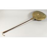 A 17TH - 18TH CENTURY DUTCH BRASS CIRCULAR WARMING PAN with metal handle. 40ins long.