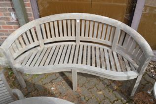 A teak curved garden bench.