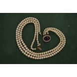 A pearl choker with yellow metal clasp, stamped 14ct, mounted with a cabochon amethyst and seed