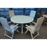 A painted circular garden table and four folding chairs.