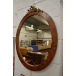 An oval mirror with decorative mount.