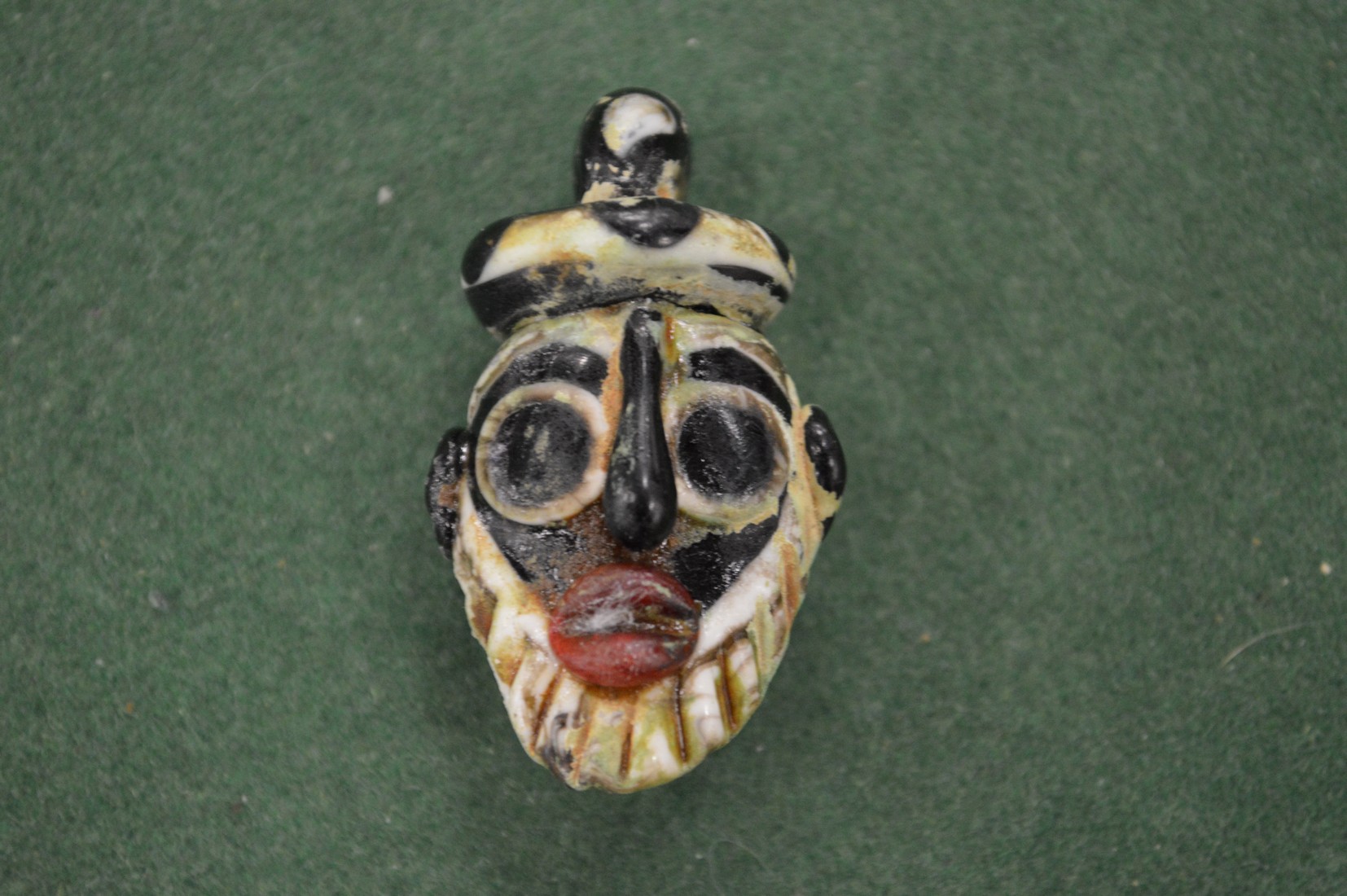 A small, possibly Roman, glass amulet modelled as a mask.