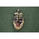 A small, possibly Roman, glass amulet modelled as a mask.