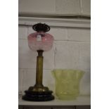 A Victorian brass oil lamp with pink glass reservoir and Vaseline glass shade.