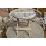 A small circular teak folding garden table.