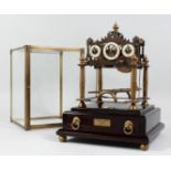 A REPRODUCTION CONGREAVE ROLLING BALL CLOCK with three dials, housed in a glass case, on a base with