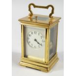 A FRENCH BRASS CARRIAGE CLOCK with eight day movement, striking on a gong, with cream enamel dial on